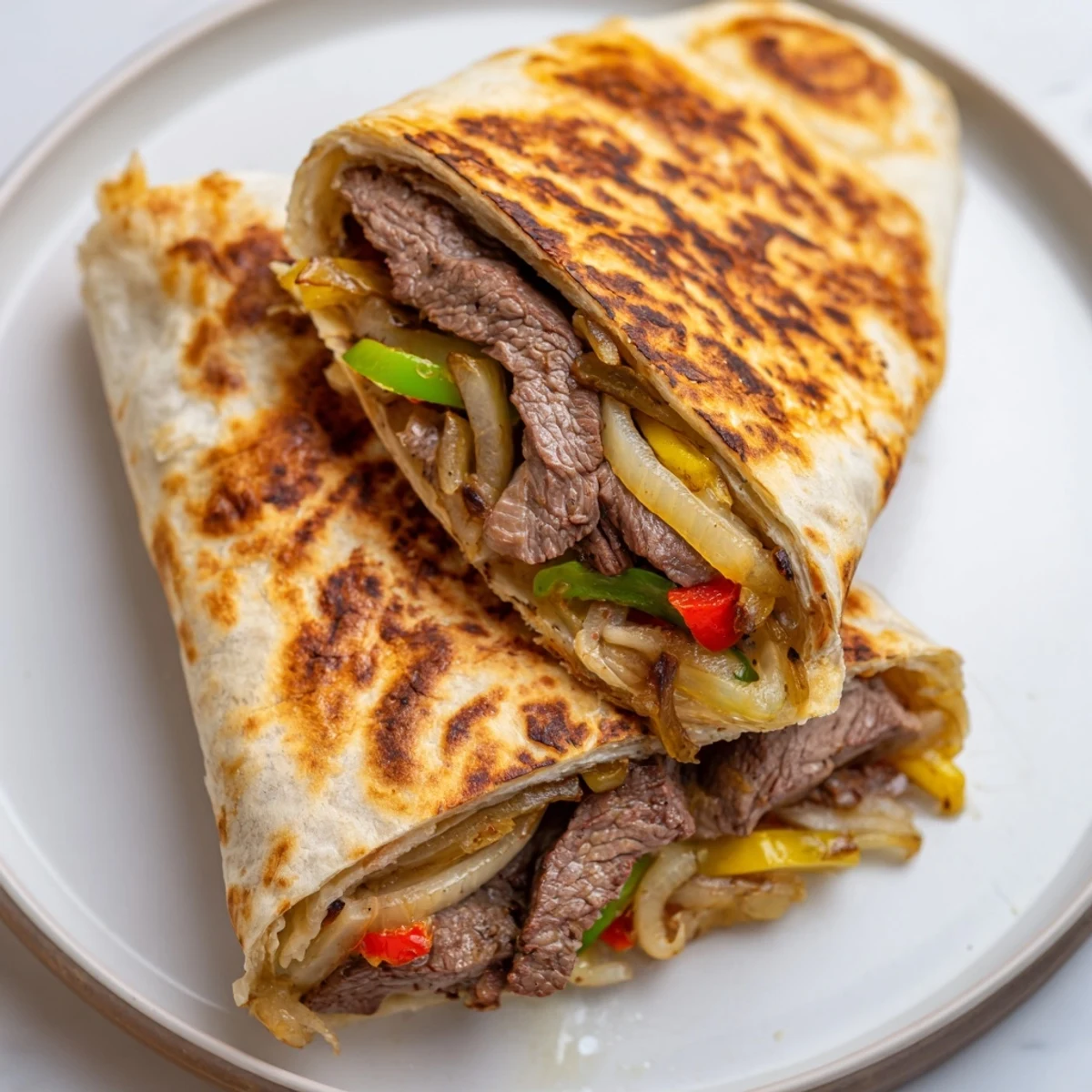 Philly cheesesteak grilled wraps sliced in half showing tender steak and melted provolone