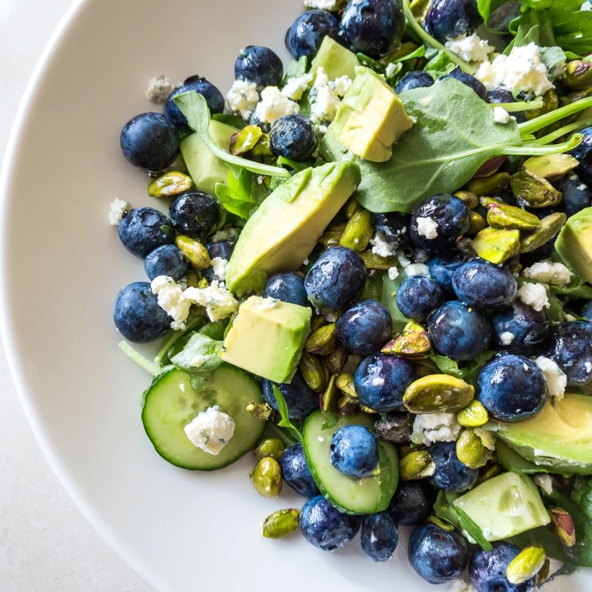 Vibrant blueberry pistachio spring salad topped with crunchy nuts and drizzled with zesty lemon dressing