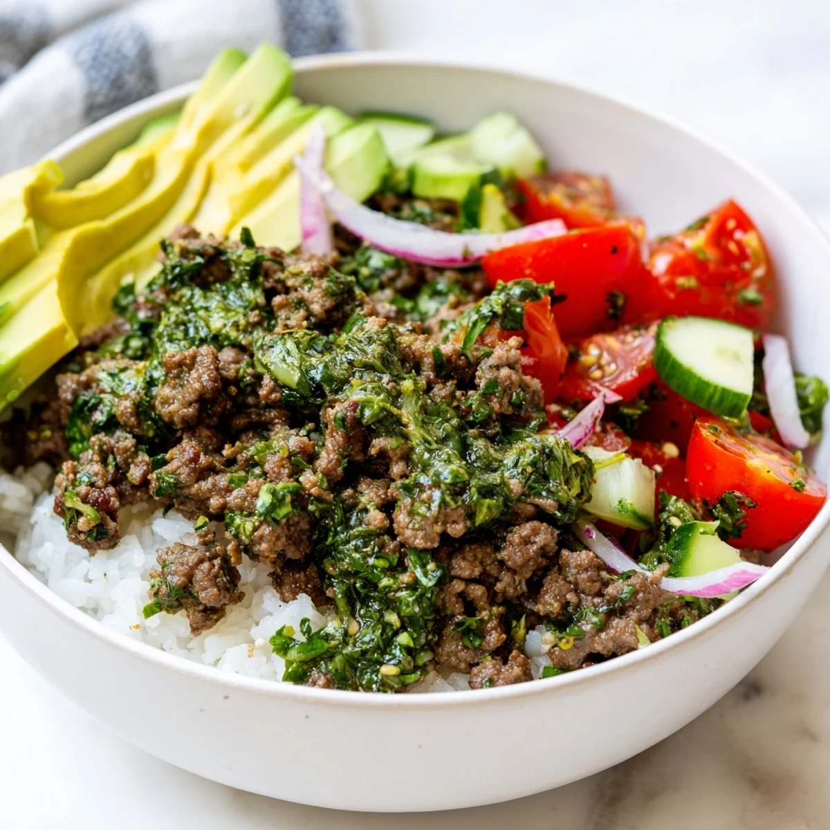 Hearty chimichurri ground beef bowls loaded with fresh avocado, tomatoes, and zesty herb sauce over fluffy white rice.