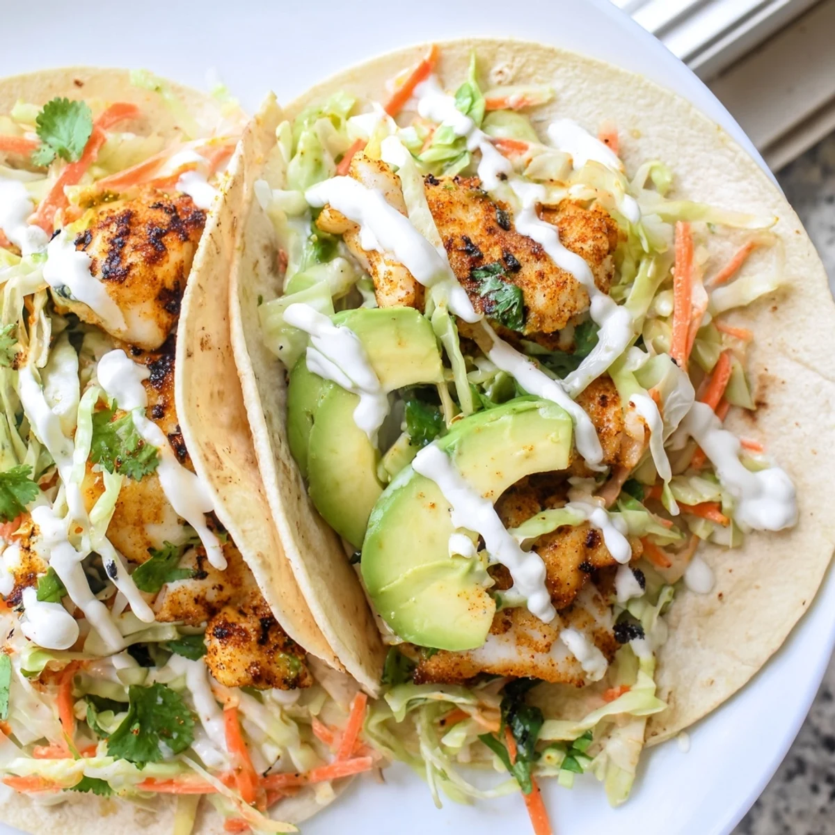Vibrant tilapia fish tacos drizzled with zesty crema and garnished with cilantro and lime