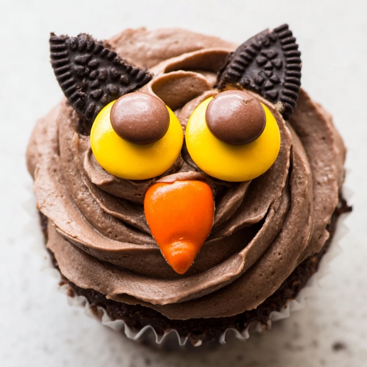 Oreo Owl Cupcakes with rich chocolate frosting and candy beaks on a rustic serving plate