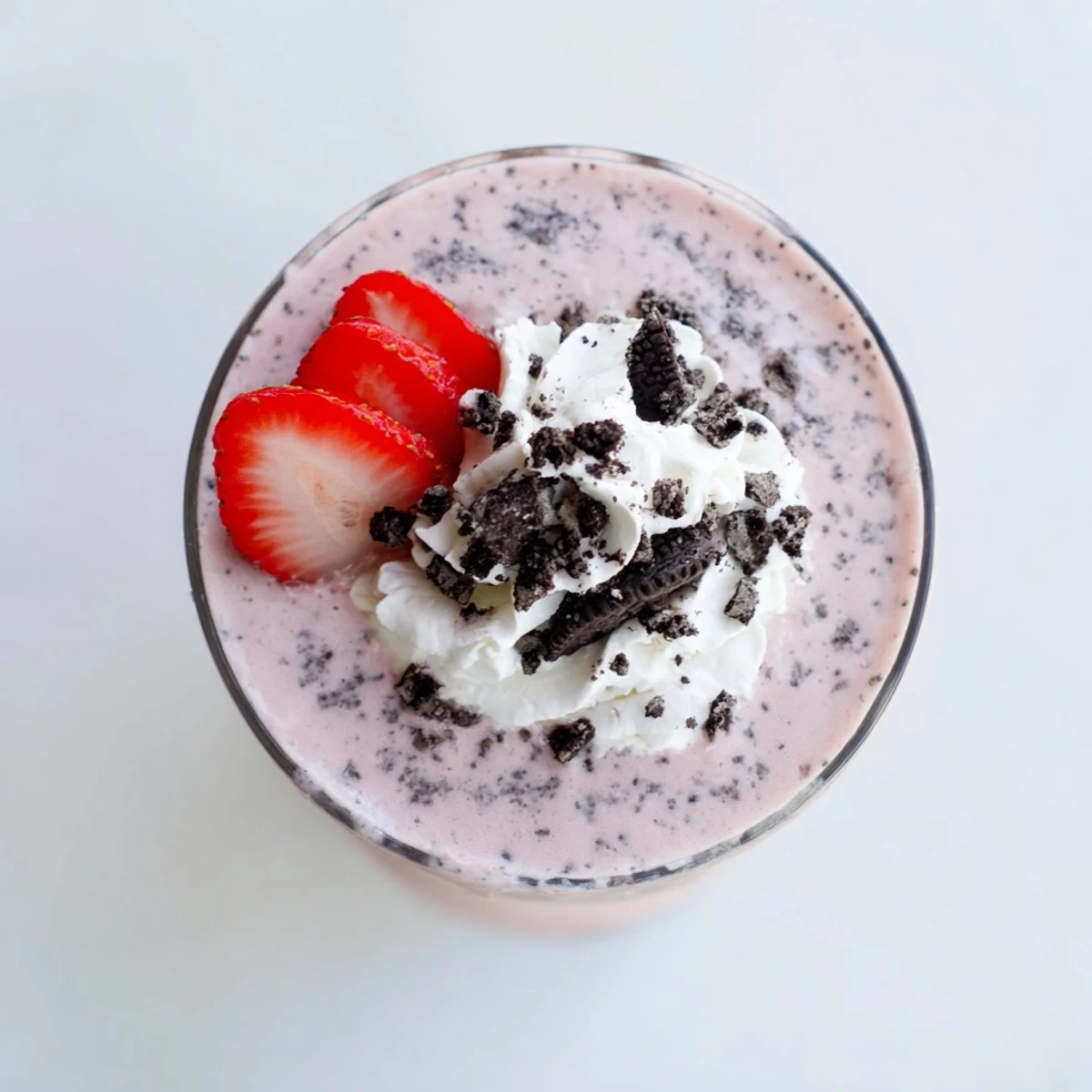 Thick pink strawberry Oreo milkshake topped with whipped cream and crushed cookies