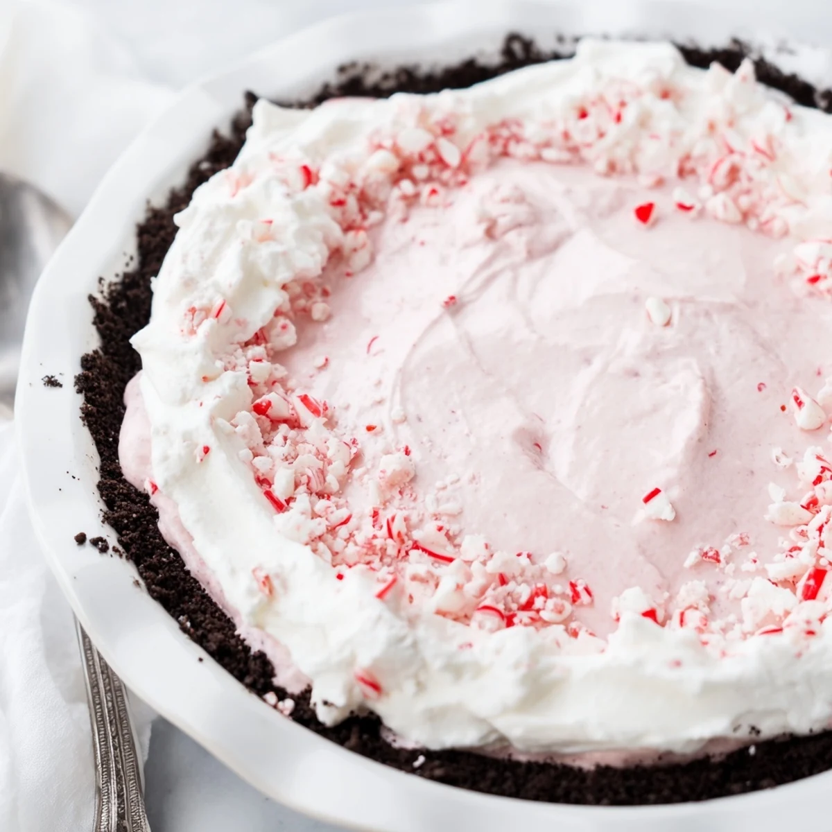 Chilled no bake Candy Cane Pie showing pink peppermint swirl and marshmallow bits.