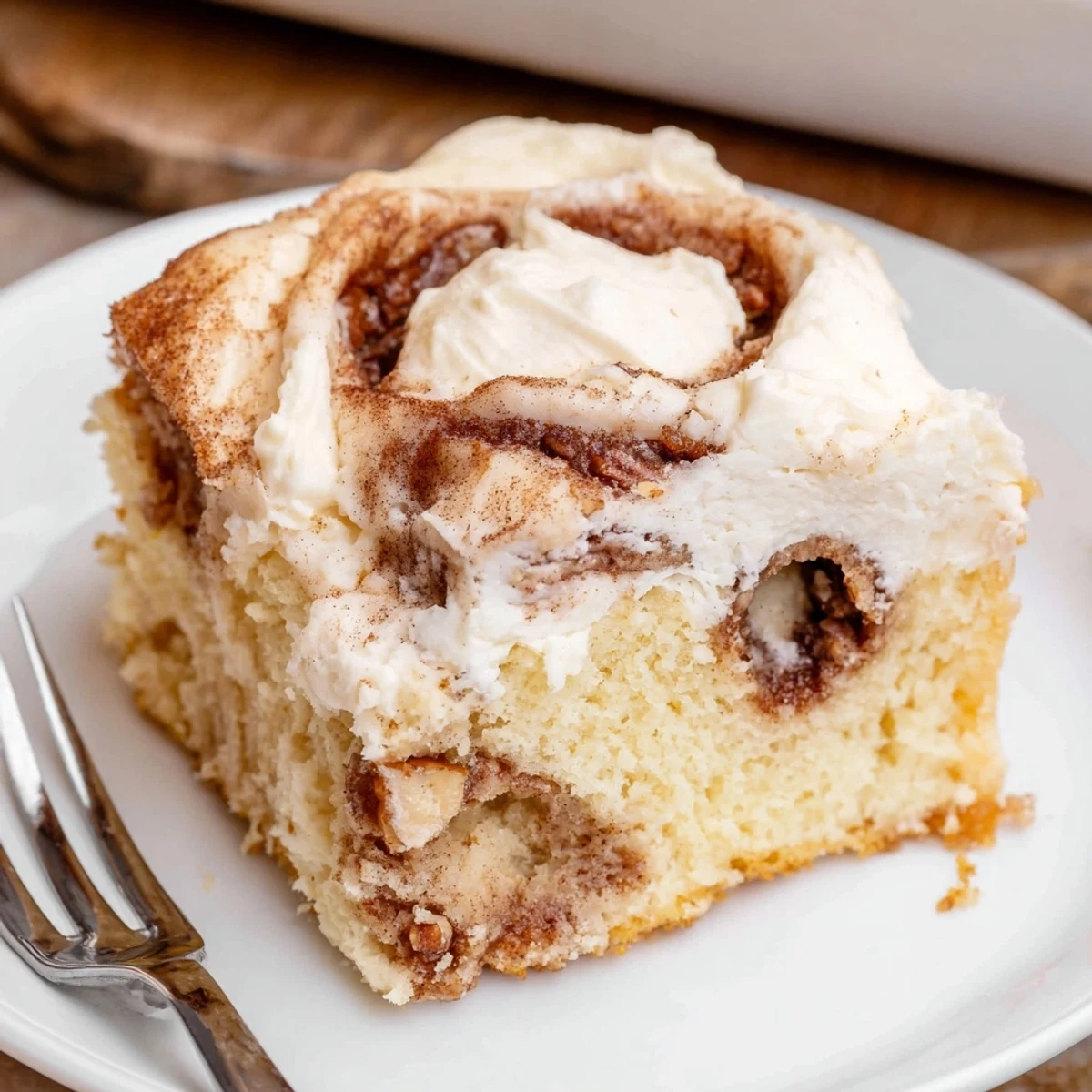 Warm Cinnamon Roll Poke Cake with gooey cinnamon swirls and cream cheese frosting