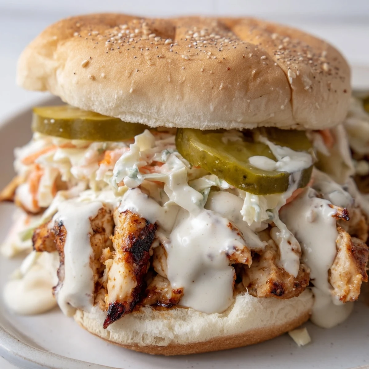 Close-up of Alabama BBQ Chicken Chopped Sandwich featuring saucy grilled chicken topped with colorful coleslaw and pickles