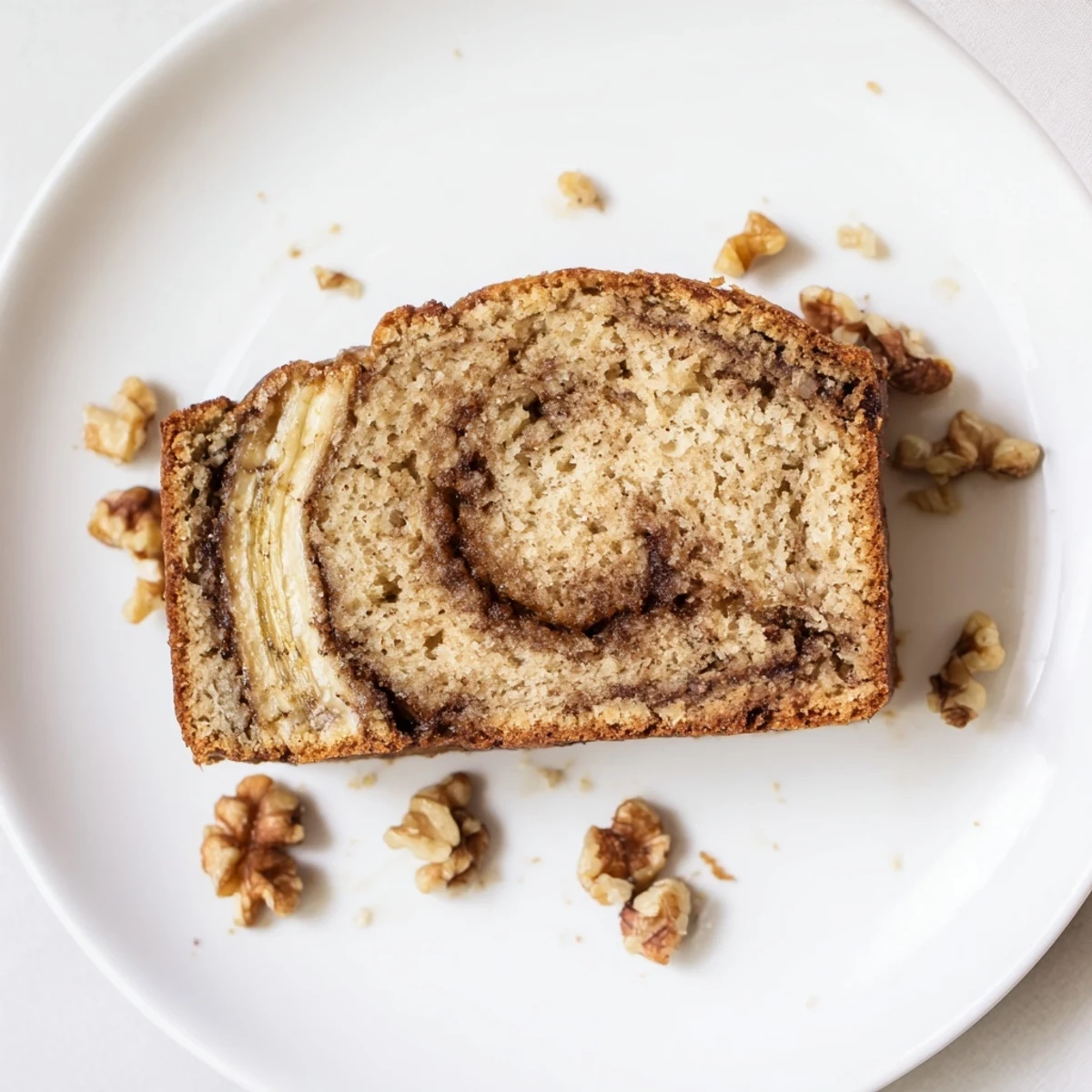 Freshly baked banana nut bread with crunchy walnuts and swirled cinnamon layer cooling on wire rack