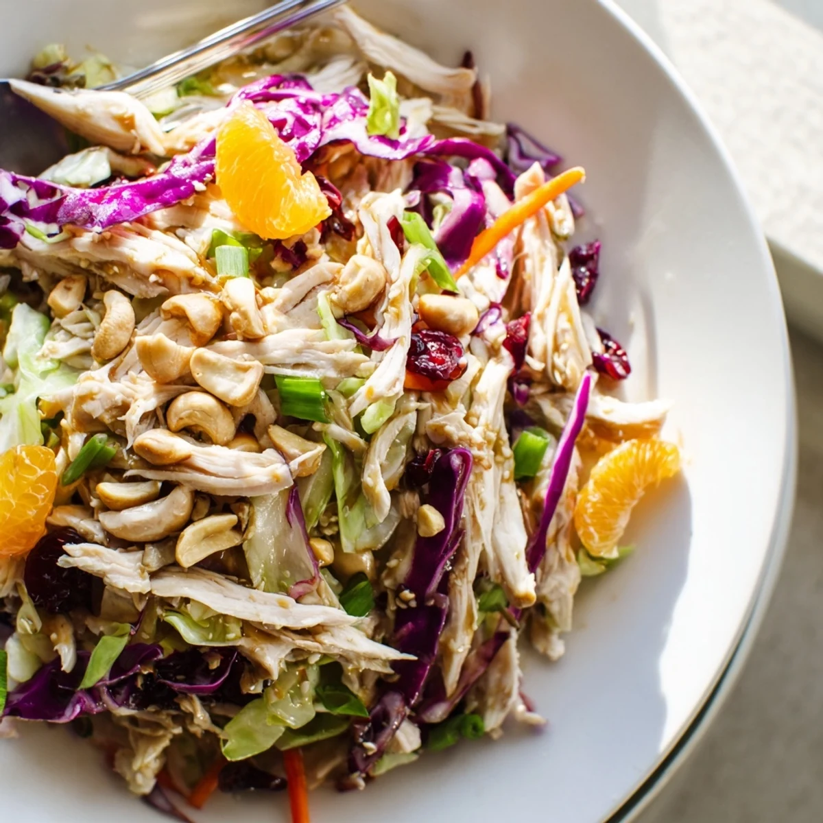 Colorful Asian chicken cranberry salad with shredded chicken, crisp cabbage, carrots, and sweet cranberries tossed in sesame dressing