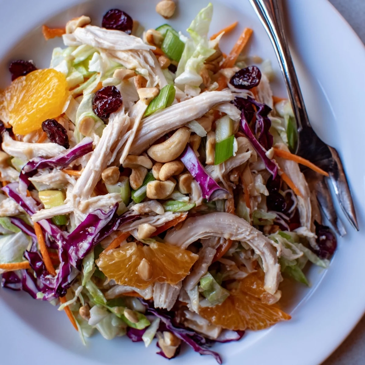 Fresh Asian chicken cranberry salad topped with roasted cashews, colorful cabbage, and tangy sesame-soy dressing