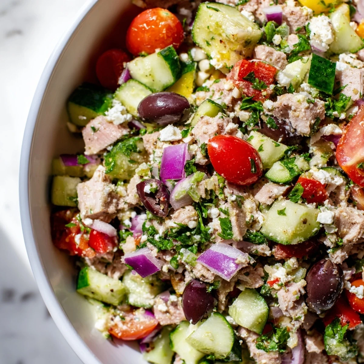 Protein-packed Mediterranean tuna salad featuring crisp cucumbers, tomatoes, and red onion drizzled with olive oil.