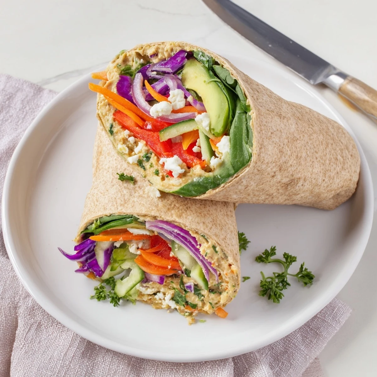 Healthy Mediterranean hummus veggie wrap sliced diagonally revealing colorful fresh vegetable layers
