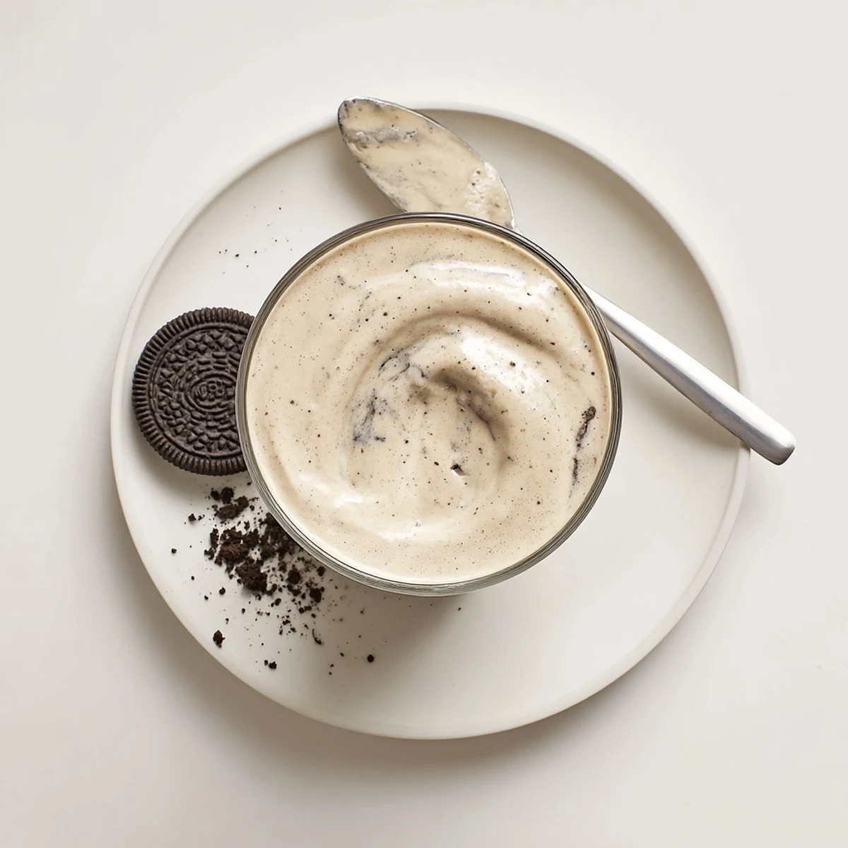 Cookies And Cream Protein Shake poured into a tall glass, speckled with crumbs