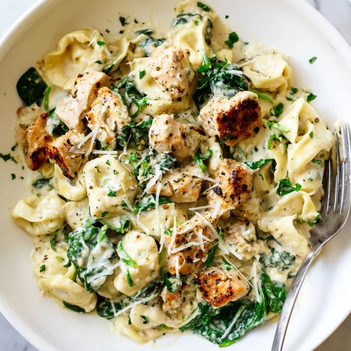 Creamy garlic chicken tortellini with spinach served in a rustic white bowl