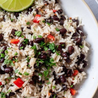 Golden Rice and Beans with Spices simmering in a pan, the vibrant red bell pepper and onion mixing with the spices.