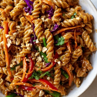 Colorful spiral pasta tossed with crisp vegetables and creamy spicy Thai peanut dressing